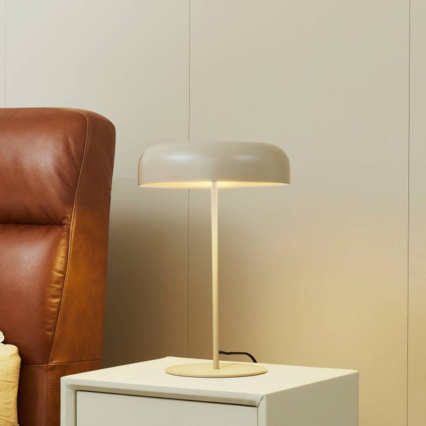 Tischleuchte auf einem Nachttisch neben einem Sessel.