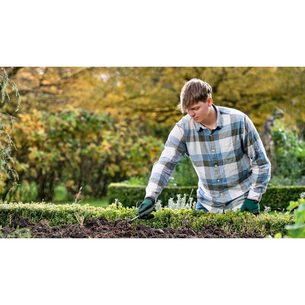 Mann arbeitet mit einem Gartenwerkzeug im Gartenbeet.