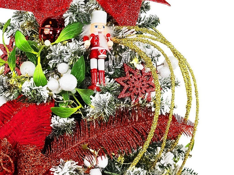 Weihnachtlicher Türkranz mit Nusschknacker, künstlichen Tannenzweigen, Beeren und glitzernden Dekorationselementen für die festliche Dekoration.