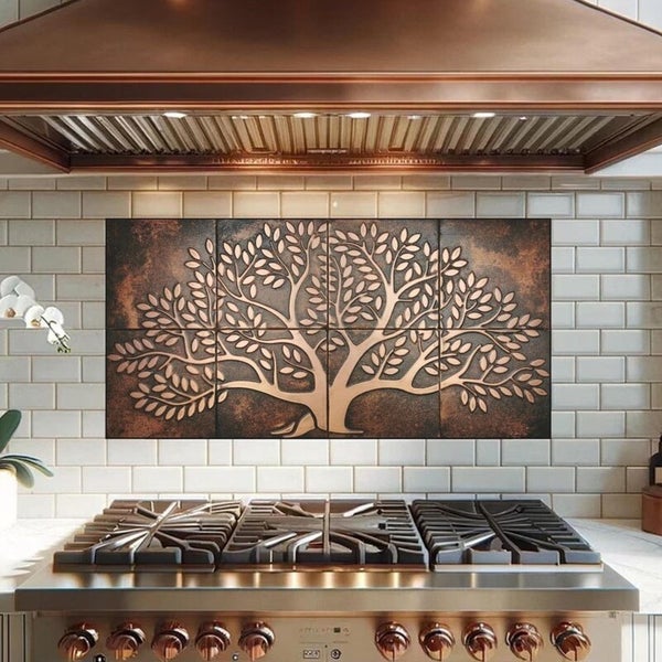 Wanddekoration mit Baum-Motiv über einem Kochfeld in einer Küche.