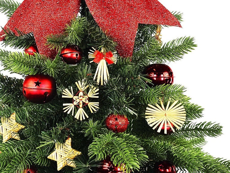 Weihnachtsbaum geschmückt mit roten glitzernden Weihnachtssternen, glänzenden roten Glocken und traditionellem Strohschmuck.