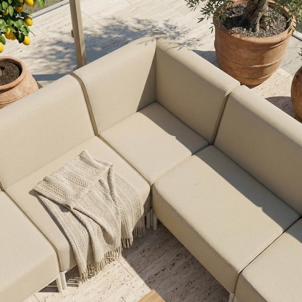 Modulares Garten-Ecksofa in Beige auf einer Steinterrasse mit gemütlicher Decke und Pflanzen in Terrakottatöpfen.