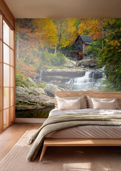 Schlafzimmer mit Fototapete, die eine Wassermühle in herbstlicher Landschaft zeigt.