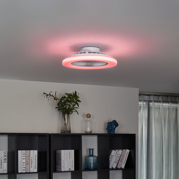 Moderner Deckenventilator mit integriertem LED-Leuchtring an der Decke in einem hellen Zimmer mit Regal und Dekoartikeln.
