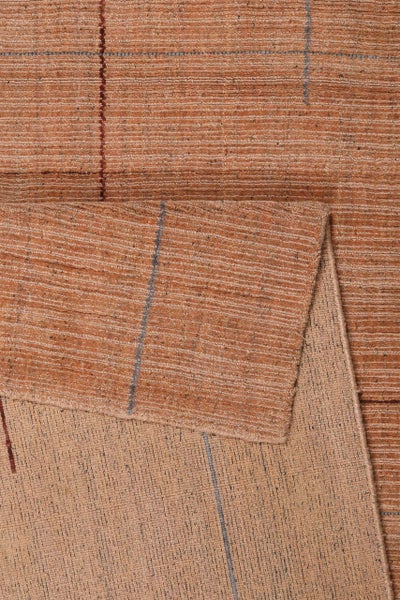 Gewebter Teppich in Terrakotta mit Rippenstruktur und Karomuster, eine Ecke ist zur Ansicht der Rückseite umgeschlagen.