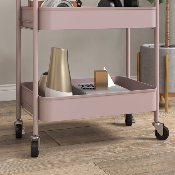 Rollbarer Etagenwagen aus Metall in Rosa mit zwei Ablagen und Lenkrollen auf einem Holzfussboden.