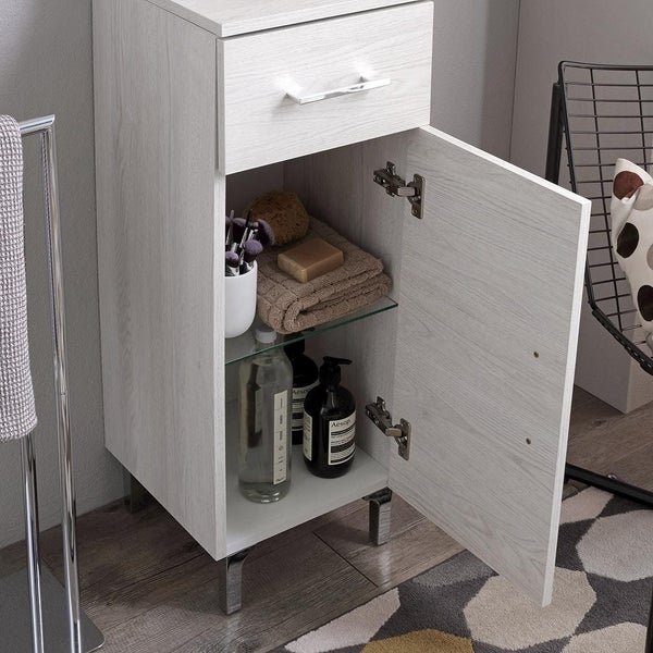 Bad-Seitenschrank in Holzoptik Weiß mit Schublade und Tür, innenliegendem Glasfach, Handtüchern und Flaschen.
