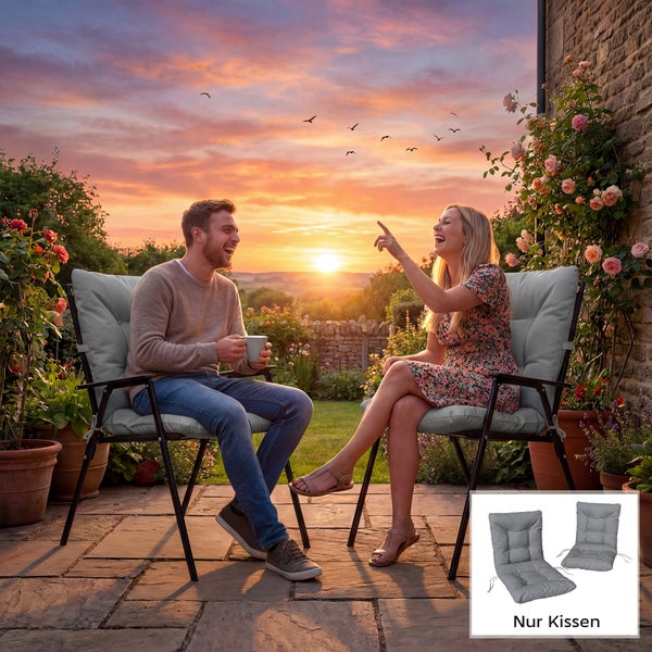 Ein Paar sitzt lachend auf Gartenstühlen mit grauen Sitzkissen auf einer Terrasse bei Sonnenuntergang.