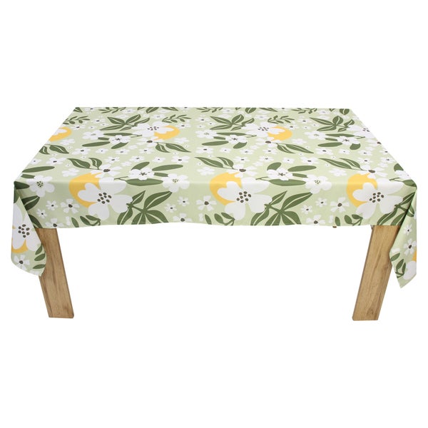 Rechteckige Tischdecke mit floralem Muster aus weißen Blüten, grünen Blättern und gelben Akzenten auf einem Holztisch.
