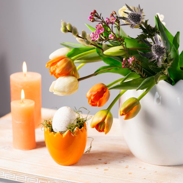Dekoratives Osterarrangement mit Tulpen, Kerzen und Osterei in Eierbecher