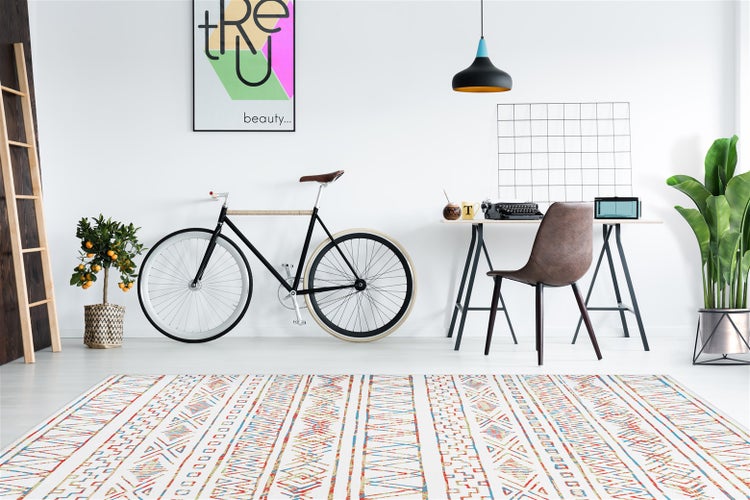 Modernes Arbeitszimmer mit buntem Webteppich, Fahrrad, Schreibtisch mit Stuhl und Pflanzen in einem hellen und stilvollen Wohnbereich.