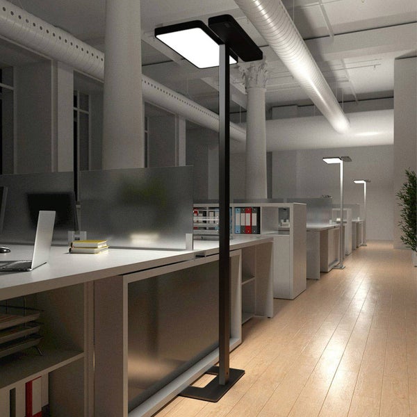 Moderne schwarze LED-Bürostehleuchte in einem hellen Großraumbüro mit Schreibtischen und Holzfußboden.