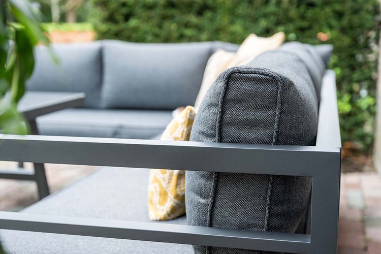 Detail eines Garten-Loungesofas mit Metallrahmen und Stoffkissen im Garten.