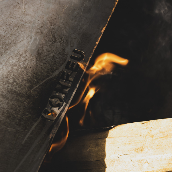 Detailansicht einer Feuerstelle mit BonFeu Logo in der Metallplatte und brennendem Feuer.