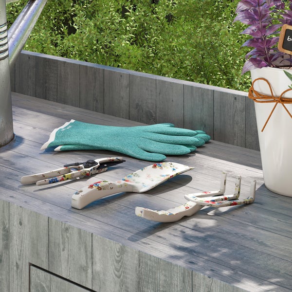 Gartenszene mit Gartenhandschuhen, Gartenschere, Schaufel und Grubber auf einem Gartentisch