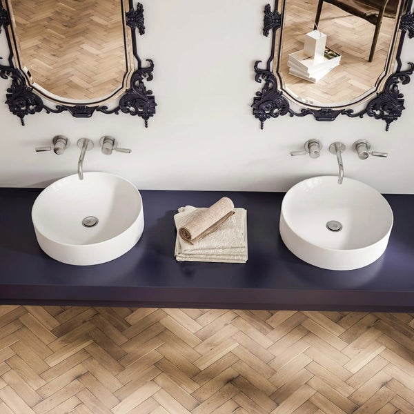 Badezimmer mit zwei Aufsatzwaschbecken, Armaturen, Handtüchern und Spiegeln mit dekorativem Rahmen.