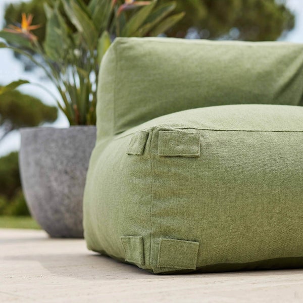 Outdoor-Loungesessel aus strukturiertem grünem Stoff mit Befestigungslaschen neben einer Pflanze in einem Steintopf auf einer Terrasse.