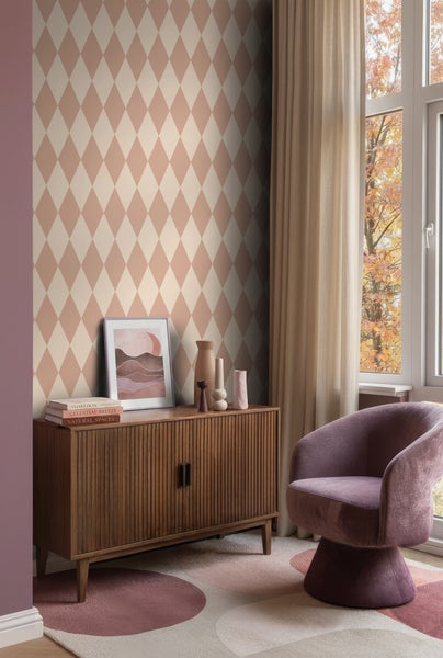 Vliestapete mit Rautenmuster in Terrakotta und Creme in einem modern eingerichteten Wohnzimmer mit Holzkommode und lila Sessel.