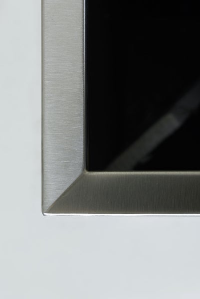 Nahaufnahme einer Ecke eines gebürsteten Metallrahmens mit schwarzer Glasfläche.