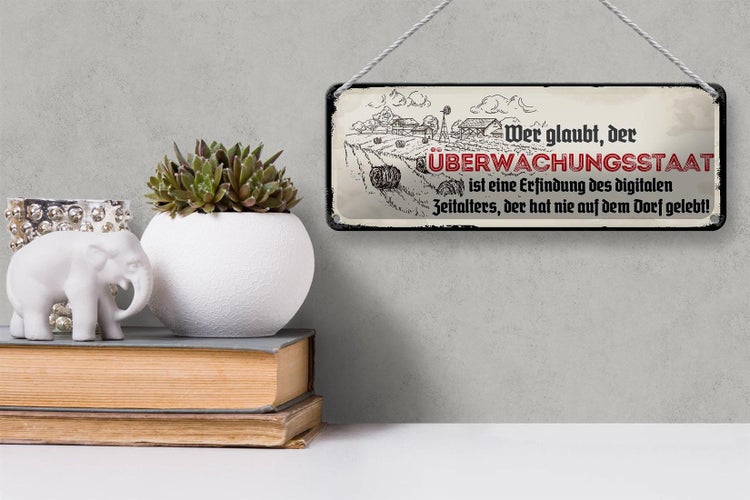Blechschild Spruch 27x10cm Überwachungsstaat Dorf Dekoration