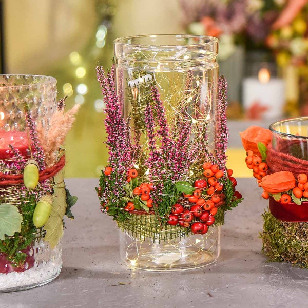 Dekoratives Glaswindlicht bestückt mit Heidekraut, roten Beeren und einer LED-Lichterkette.