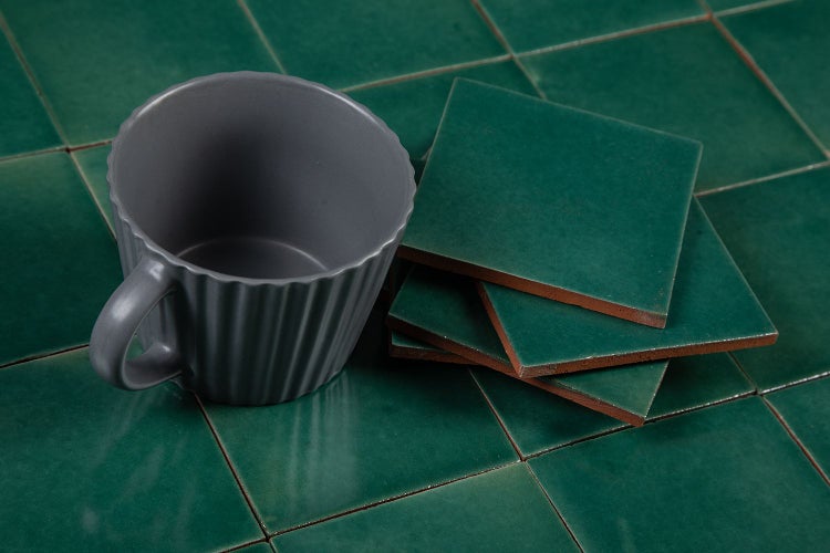 Graue Tasse und grüne quadratische Fliesen