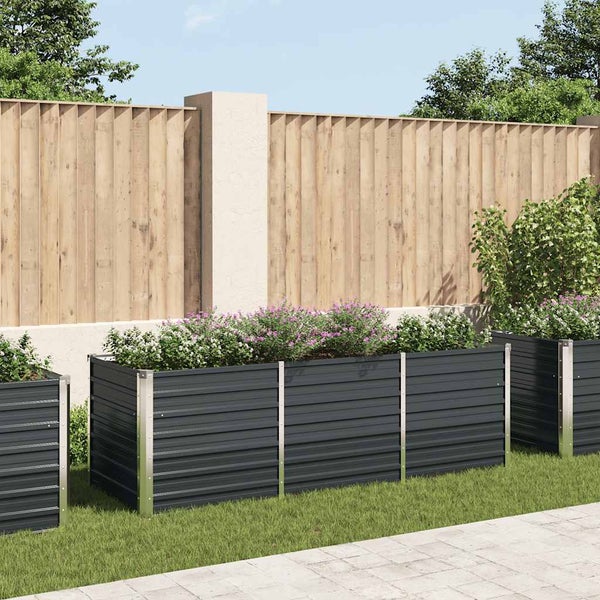 Modernes Hochbeet aus Metall in Anthrazit, bepflanzt mit Blumen in einem Garten vor einem Holzzaun.