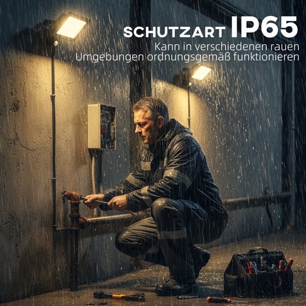 Zwei helle LED-Fluter beleuchten einen Handwerker bei Reparaturarbeiten an einem Rohr im Regen, Schutzart IP65 für den Außenbereich.