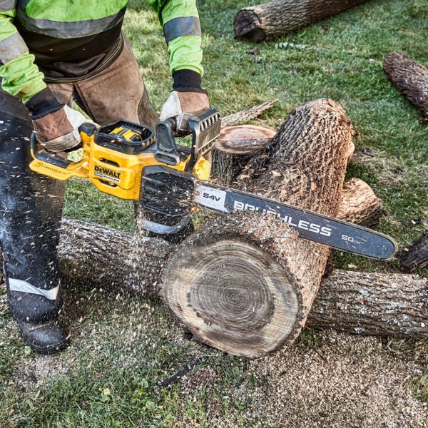 Person schneidet mit einer DeWalt 54 Volt Akku-Kettensäge mit 50 Zentimeter Schwertlänge einen dicken Baumstamm im Freien.