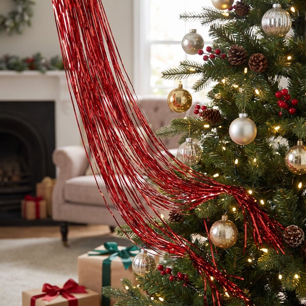 Geschmückter Weihnachtsbaum mit glänzendem Lametta in einem gemütlich eingerichteten Wohnzimmer mit Kamin und Geschenkverpackungen.