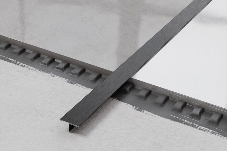 Detailaufnahme einer grauen Übergangsschiene zwischen zwei Bodenbelägen