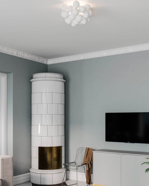 Wohnzimmer mit Kachelofen, Deckenleuchte mit Kugeldesign, Zierleisten und einem Fernsehgerät