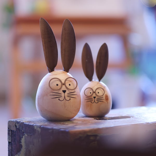 Zwei hölzerne Osterhasenfiguren mit Gesicht und Brille