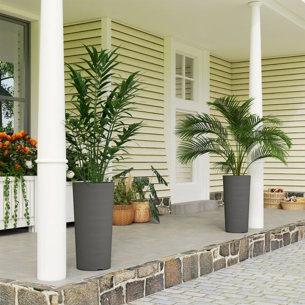 Hohe, anthrazitfarbene Pflanzkübel mit Palmen auf einer hellen, organisierten Veranda mit weißen Säulen.