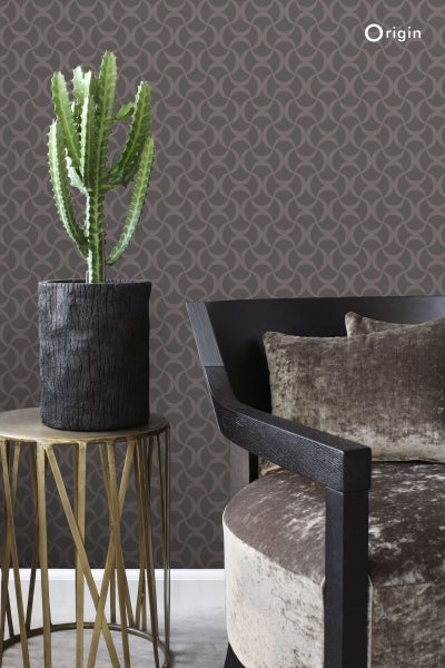 Dekorative Szene mit Kaktus in dunklem Pflanzgefäß, Beistelltisch mit Metallgestell, Sessel und gemusterter Tapete.