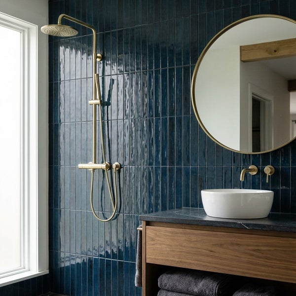 Modernes Badezimmer mit hochglänzenden Wandfliesen, Waschtisch aus Holz, rundem Spiegel und goldfarbenem Duschsystem sowie Armaturen.