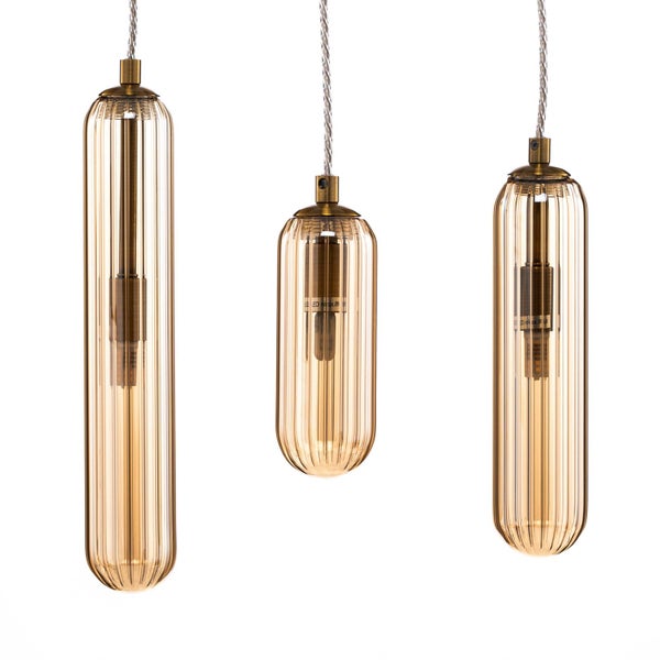 Drei Pendelleuchten mit geriffelten Glasschirmen in Bernsteinfarben und Messing-Elementen in verschiedenen Längen.