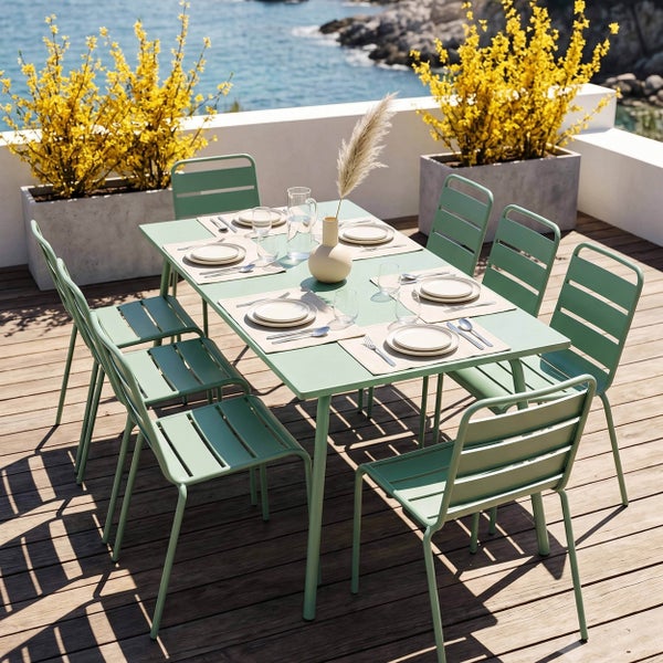 Hellgrünes Gartenmöbel-Set aus Metall auf einer Terrasse, mit einem rechteckigen Esstisch und sechs Stühlen im Latten-Design.