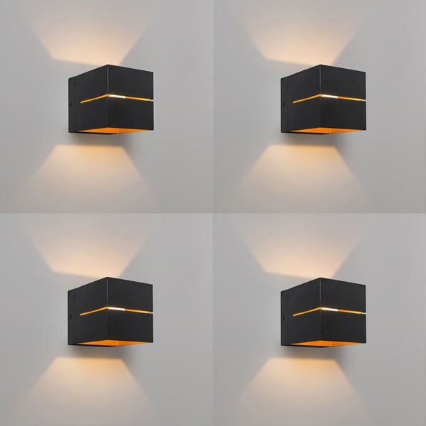 Vier schwarze, würfelförmige Wandleuchten an einer Wand