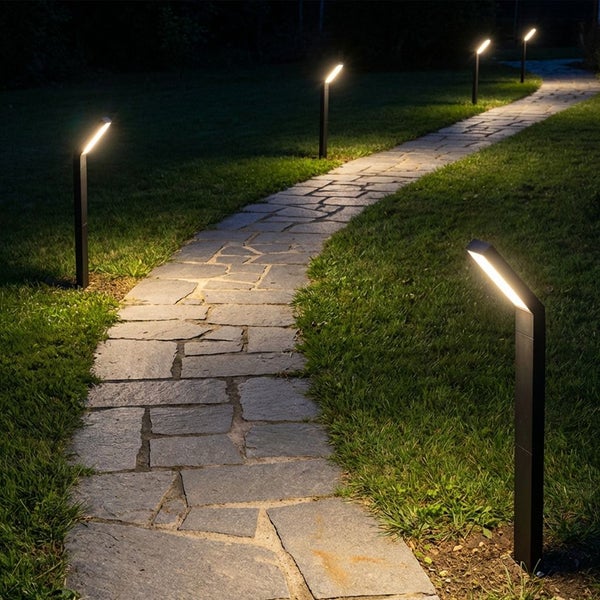 Moderne schwarze LED Wegleuchten beleuchten einen geschwungenen Steinpfad im Garten bei Nacht.