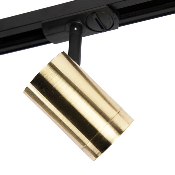 Zylindrischer Strahler in Gold für ein schwarzes Schienensystem.