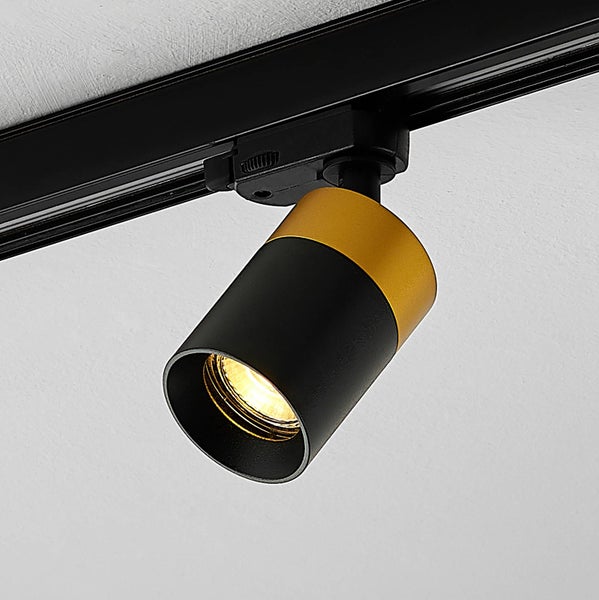 Strahler für Schienensystem, zylindrisch, schwarz und gold, eingeschaltet mit warmem Licht.