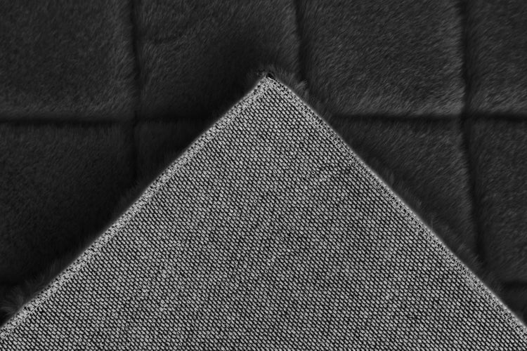 Nahaufnahme eines Teppichs mit gewebter Unterseite und weicher Oberfläche in Felloptik.