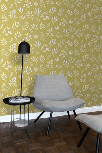 Wohnzimmer mit gemusterter Tapete, Sessel, Hocker, Tischlampe und Beistelltisch