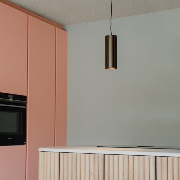 Moderne Küche mit Hängelampe, rosa Schränken und einer Kücheninsel mit Holzverkleidung.