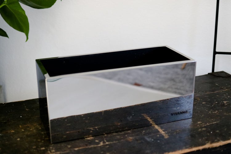 Rechteckiger Pflanzkübel aus poliertem Edelstahl mit spiegelnder Oberfläche und Vivanno Logo auf einer Holzplatte.