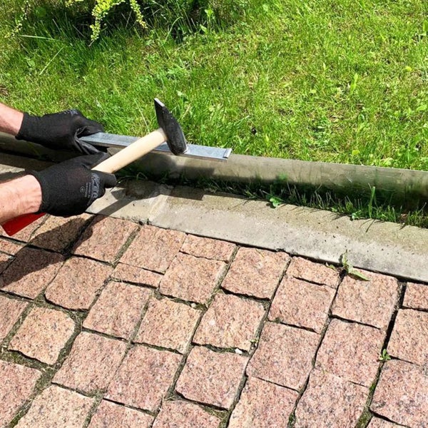 Gartenarbeitsszene mit Hammer, Metallschiene und Pflastersteinen
