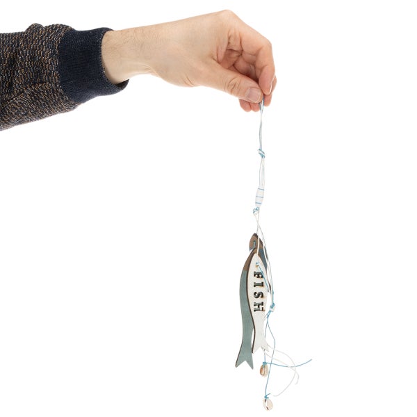 Hand hält eine Hängedekoration mit Fischen aus Holz und kleinen Muscheln.