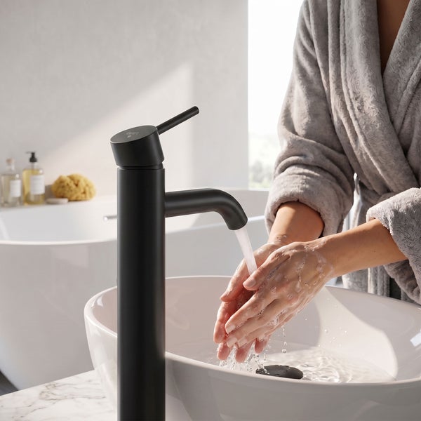 Person wäscht Hände an einem weißen Aufsatzwaschbecken mit einer hohen matt schwarzen Waschtischarmatur in einem modernen, hellen Badezimmer.