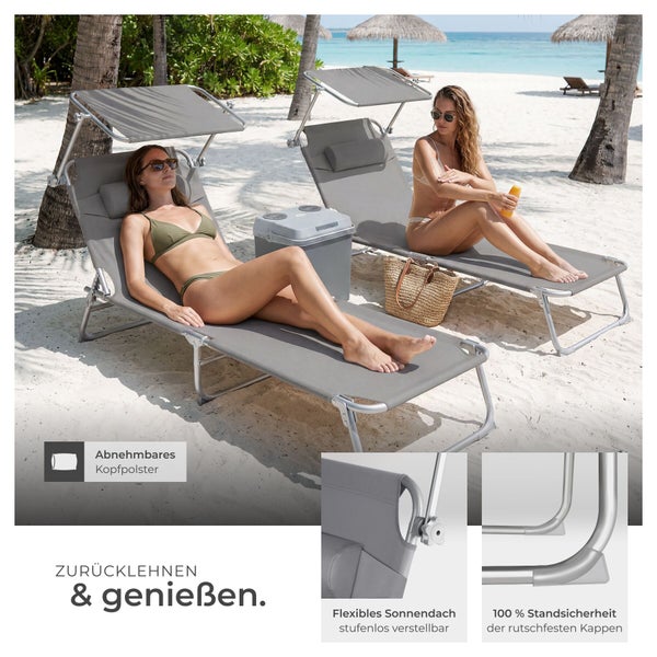 Zwei graue Sonnenliegen mit verstellbarem Sonnendach und Kopfpolster am Strand, stabiles Aluminiumgestell mit rutschfesten Kappen.